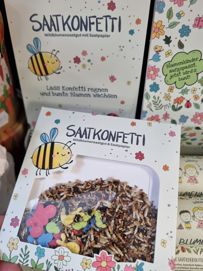 Verpackung von Saatkonfetti mit Bienen- und Blumenillustrationen in lebhaften Farben.