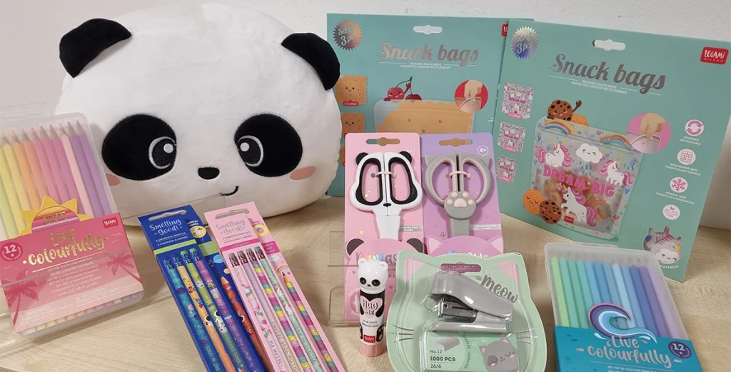 Bunte Schreibwaren mit Panda- und Katzenmotiven auf einem Tisch, darunter Kissen, Stifte und Scheren.