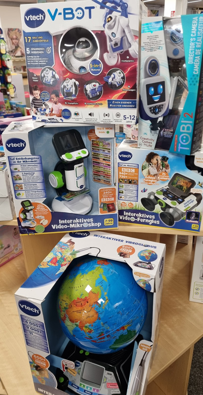 Bunte VTech-Spielzeuge im Geschäft: Roboter, Mikroskop, Fernglas und interaktiver Globus für Kinder.