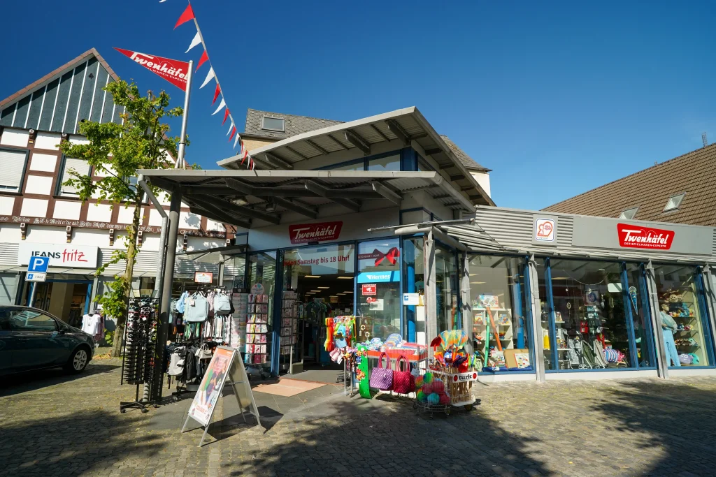 Ein Geschäft namens "Twenhäfel" mit bunten Waren und Verkaufsständern vor großen Glasfenstern.