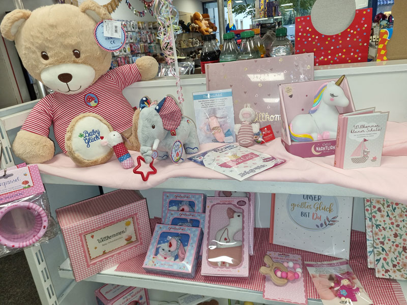 Dekorative Baby-Auslage mit Plüschtieren, Spielzeugen und Büchern in sanften Pastelltönen.