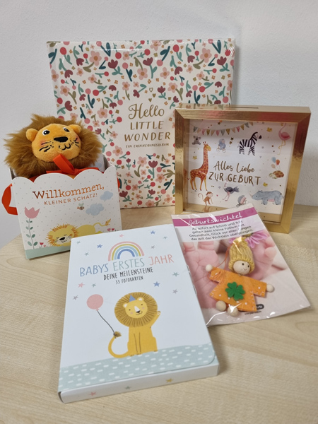 Geschenke zur Geburt: Plüschlöwe, Geschenkbox, Bilderrahmen, Buch und Holzengel in Pastellfarben.