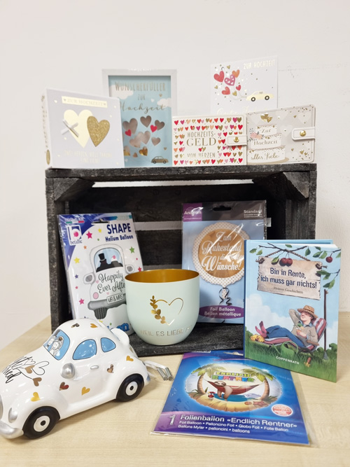 Geschenke und Karten für Hochzeiten und Ruhestand auf Holzkasten, mit Herzen und festlichen Motiven.